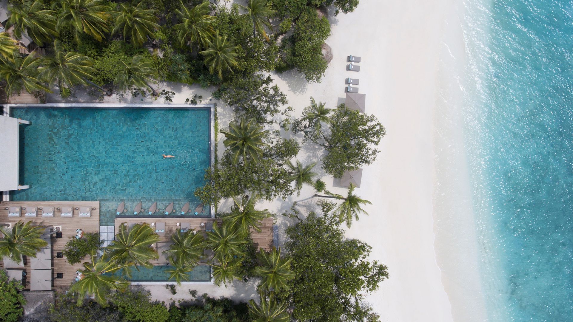 Outdoor pool of Vakkaru Maldives resort with sun bed area