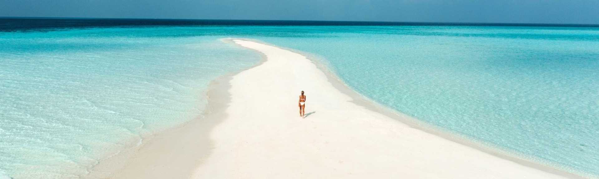 A girl walking on middle of white sand beach at Maldives